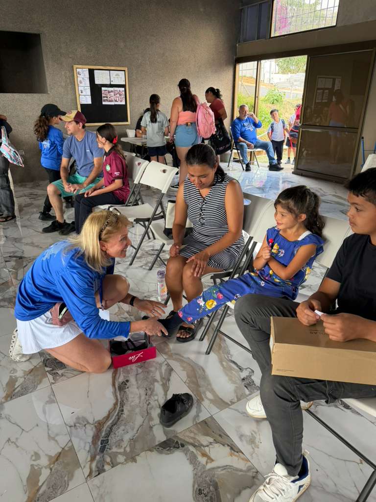 A volunteer kneeling to fit a child with new shoes during outreach